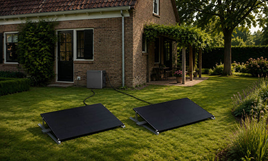 Twee plug en play zonnepanelen in de tuin bij een woning, met elk een kabel naar een compacte thuisbatterij.