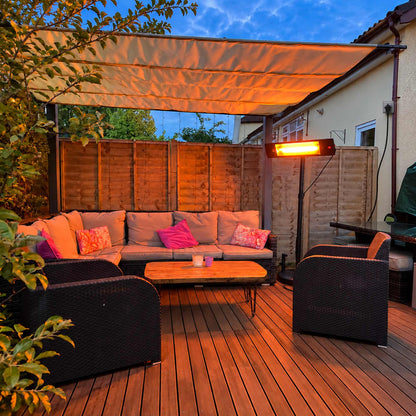 Zwarte Herschel COLORADO 2500 W infrarood terrasverwarmer op zwarte standaard bij een loungeset onder een overkapping