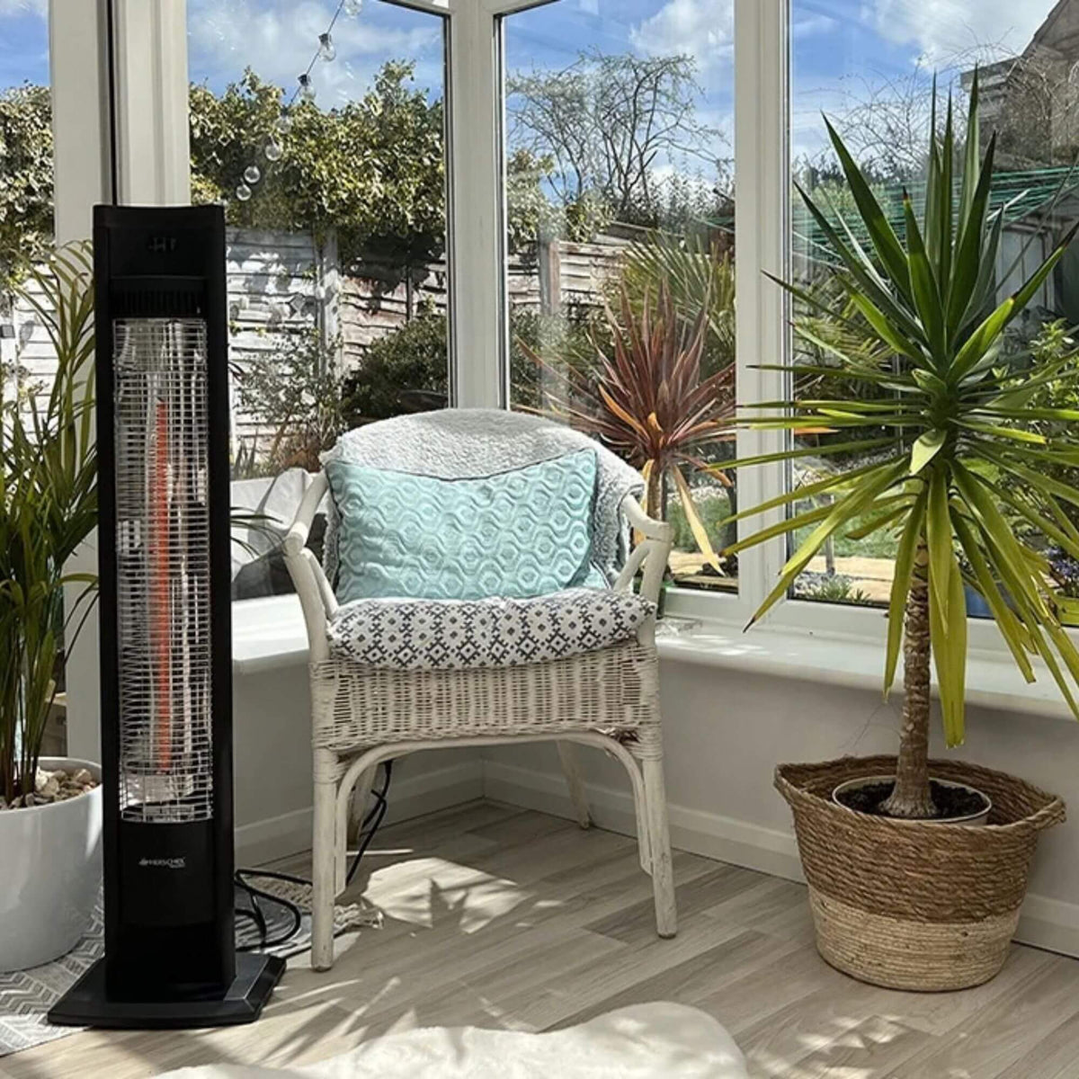 Bediening van de Herschel MALIBU 2000 W, zwarte infrarood terrasverwarmer in een veranda bij een stoel.
