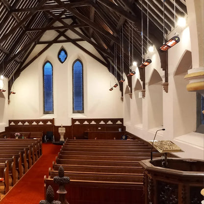 Zwarte MANHATTAN 3000 W verwarmers hangen aan de muren van een kerk.