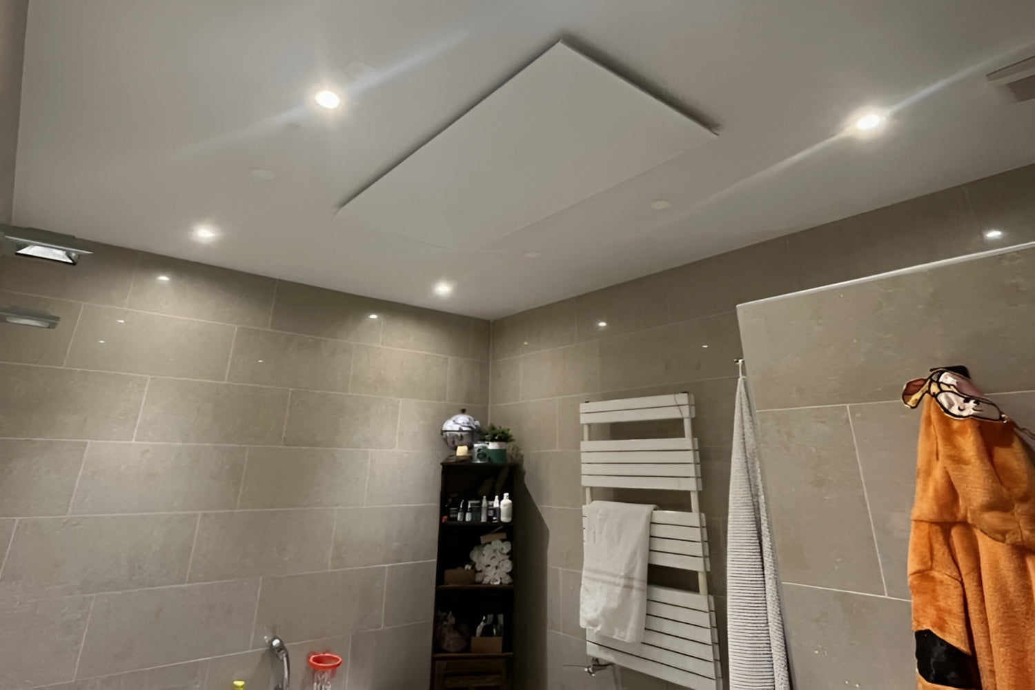 Wit Nova infrarood verwarmingspaneel gemonteerd aan het plafond in een badkamer