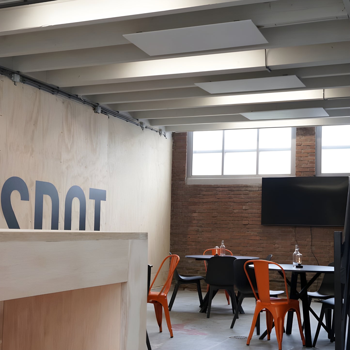 3 witte Nova infrarood verwarmingspanelen gemonteerd aan het plafond in een vergaderruimte met tafel en stoelen