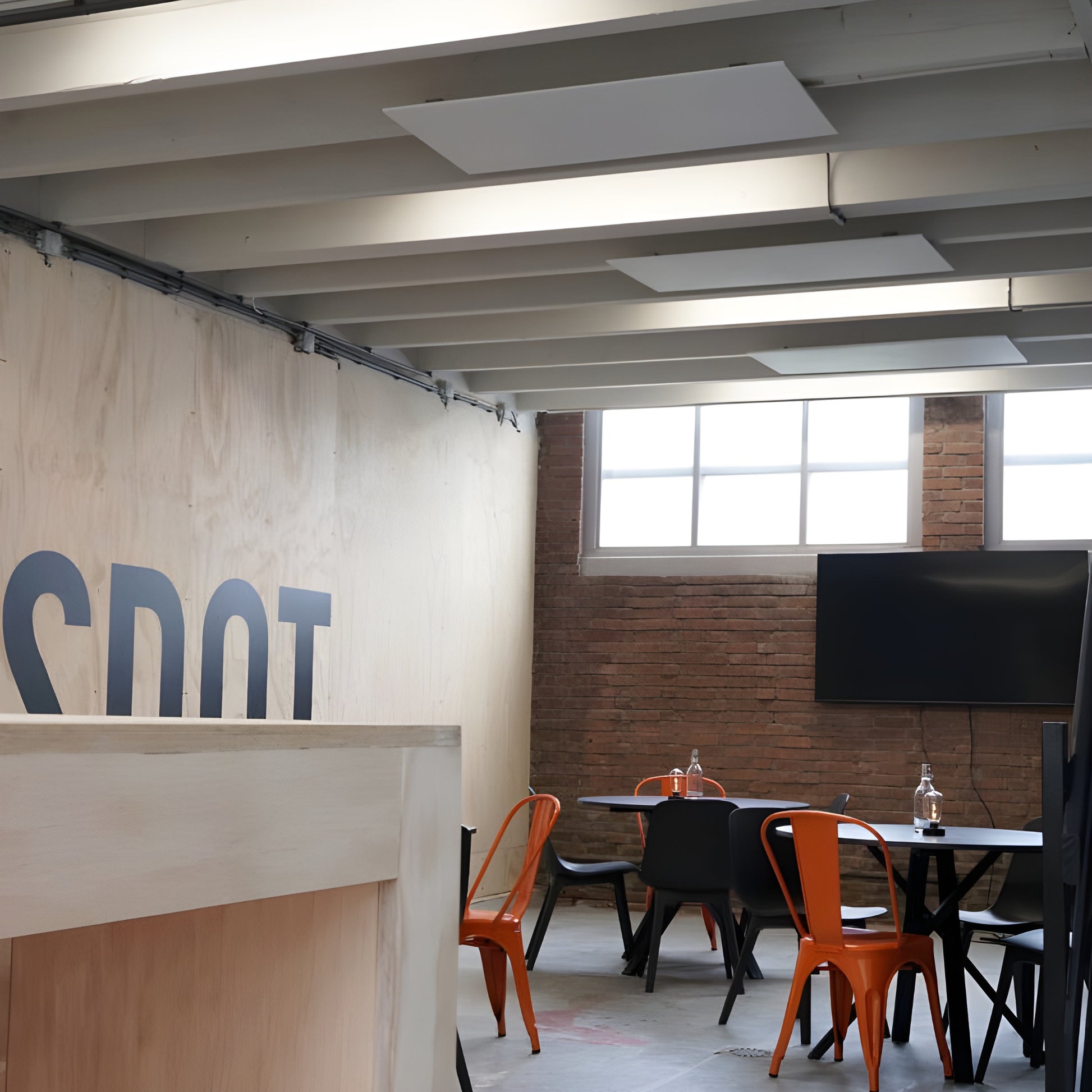 3 witte Nova infrarood verwarmingspanelen gemonteerd aan het plafond in een vergaderruimte met tafel en stoelen